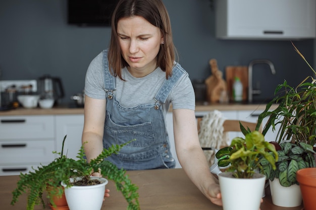 Ein junges Mädchen in der Küche pflanzt selbstgemachte Grünpflanzen in Töpfe um