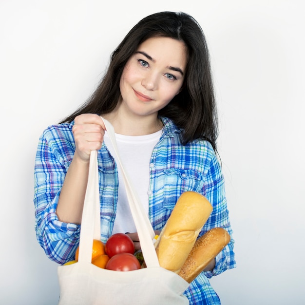 Ein junges Mädchen in einem blauen Hemd hält eine Stofftasche mit Essen