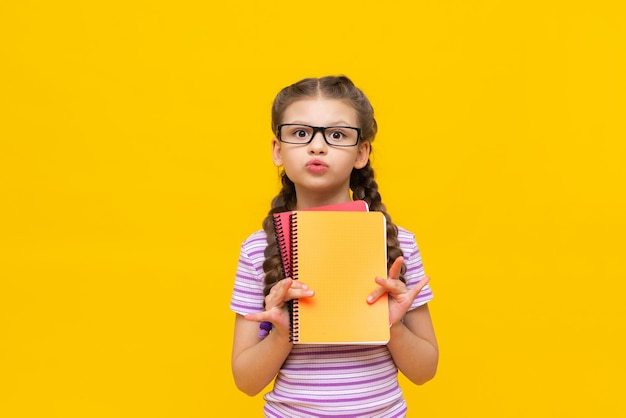 Ein junges Mädchen in einem lila gestreiften T-Shirt hält zwei Notizbücher und ist überrascht