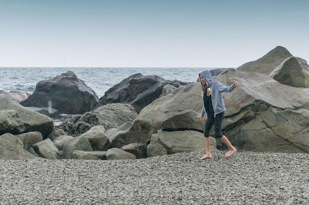 Ein junges Mädchen in einem Pullover auf einem tobenden kalten Meer Ruhen Sie sich bei schlechtem Wetter auf dem Meer aus