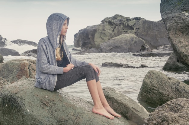 Ein junges Mädchen in einem Pullover auf einem tobenden kalten Meer Ruhen Sie sich bei schlechtem Wetter auf dem Meer aus