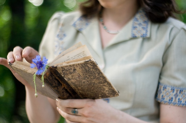 Ein junges Mädchen in einem Vintage-Kleid, das altes Buch hält