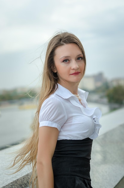 Ein junges Mädchen in einem weißen Hemd posiert in der Stadt