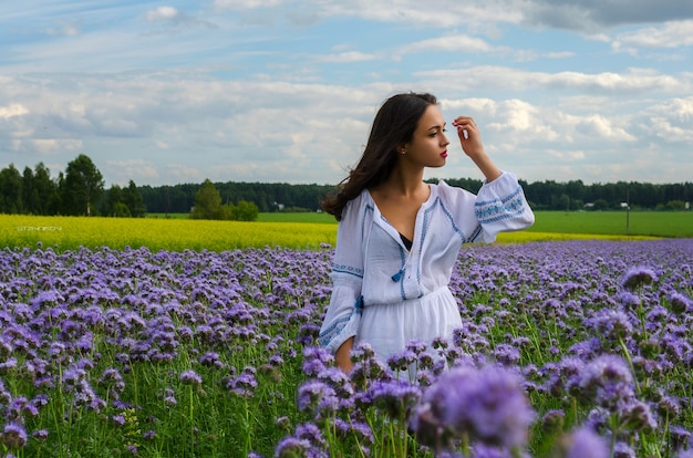 Ein junges mädchen in einem weißen kleid in einem blumenfeld.