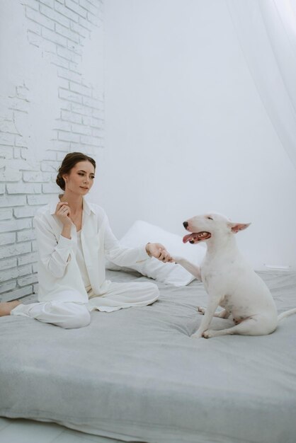 ein junges Mädchen in einem weißen Zimmer spielt mit einem Hund