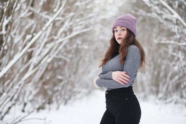 Ein junges Mädchen in einem Winterpark bei einem Spaziergang. Weihnachtsferien im Winterwald. Mädchen genießt den Winter im Park.