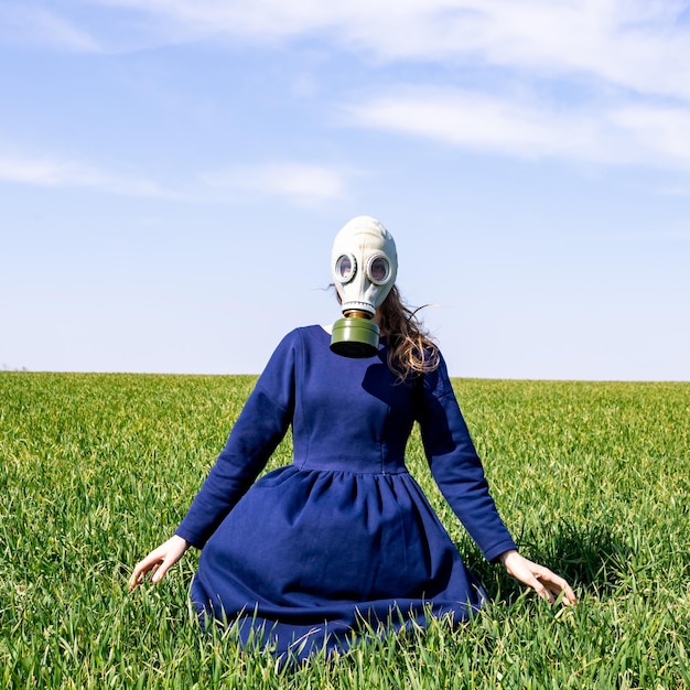 Ein junges Mädchen in einer Gasmaske steht auf einem grünen Feld. Pandemie. Coronavirus.