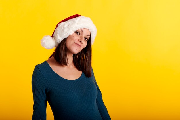Ein junges Mädchen in einer Weihnachtsmannmütze mit gelbem Hintergrund