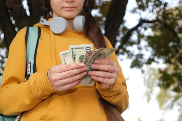 Ein junges Mädchen in Kopfhörern zählt das Taschengeld der Dollarnoten