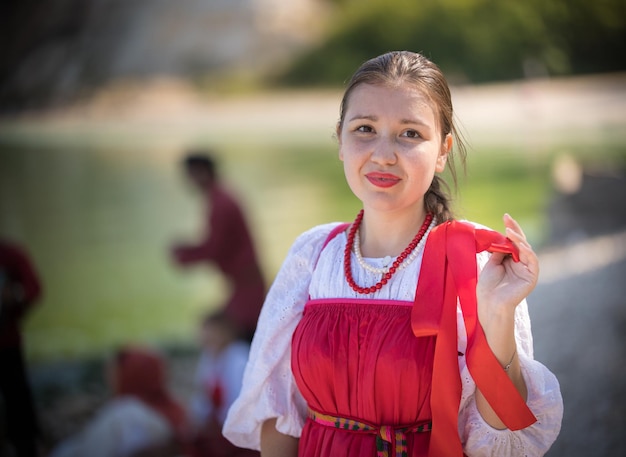 Ein junges Mädchen in russischer Tracht schaut in die Kamera, hinter ihren Freunden, Nahaufnahme