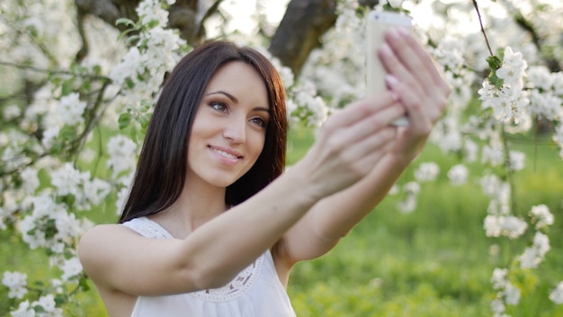 Ein junges Mädchen macht im Frühjahr ein Selfie in einem Apfelgarten.