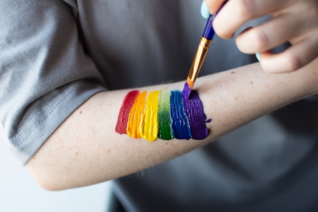 Ein junges Mädchen malt sich als Zeichen der Solidarität einen Regenbogen mit leuchtenden Farben auf die Hand