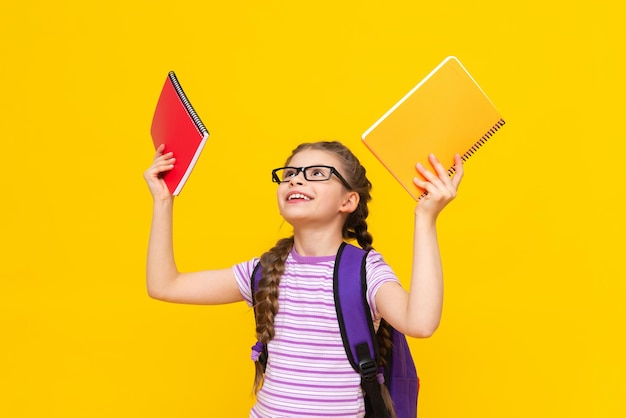 Ein junges Mädchen mit bunten Notizbüchern in ihren Händen und einer Brille. Ein kleines Mädchen bereitet sich auf die Schule vor. Zusätzliche Kurse für das Kind