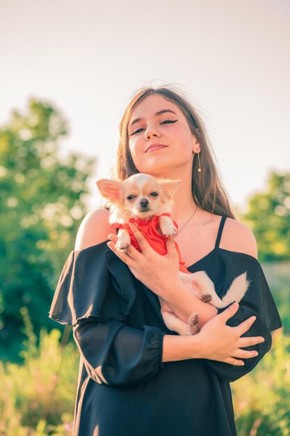 Ein junges Mädchen mit einem Chihuahua-Hund im Arm Haustier und Besitzer vor dem Hintergrund der Natur