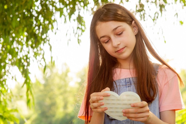 Ein junges Mädchen mit einem Pop-It-Spielzeug in ihren Händen. Mädchen in der Natur.