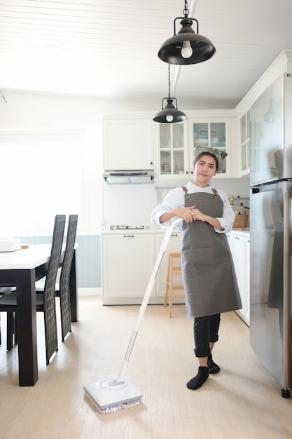 Ein junges Mädchen putzt das Haus mit einem Mopp. Es gibt eine Küchenkulisse