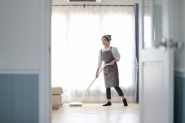 Ein junges Mädchen putzt das Haus mit einem Mopp. Es gibt eine Küchenkulisse