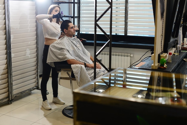 Ein junges Mädchen schneidet Mann im Barbershop