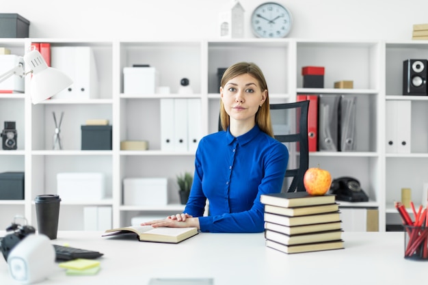 Ein junges Mädchen sitzt am Tisch. Vor dem Mädchen liegt ein offenes Buch.