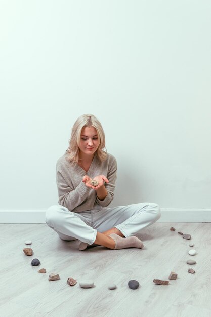 Ein junges Mädchen sitzt auf dem Boden, umgeben von einem Steinkreis Psychisches Gesundheitskonzept