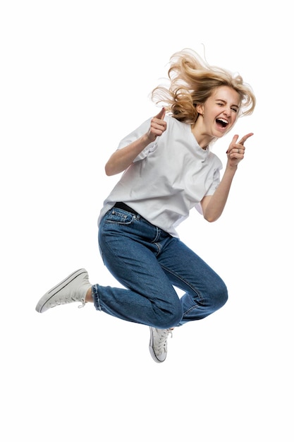 Ein junges Mädchen springt Lachendes Mädchen in einem weißen T-Shirt und Blue Jeans Aktivität und positiv Isoliert auf weißem Hintergrund Vertikal