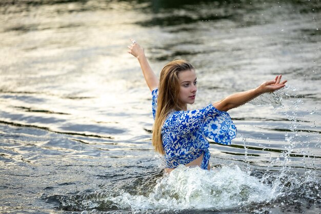 Foto ein junges mädchen spritzt auf einem heißen sommerabend im flusswasser