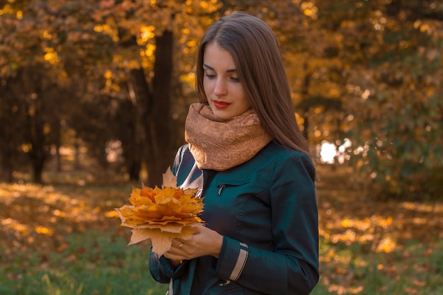 Ein junges mädchen steht im park und hält einen blumenstrauß in den händen der nahaufnahme