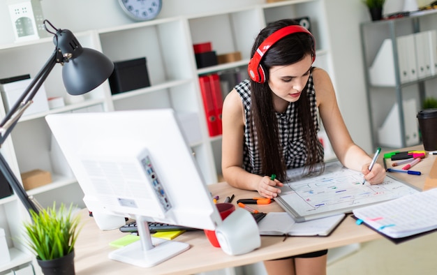 Ein junges Mädchen steht neben einem Tisch, hält einen grünen Stift in der Hand und arbeitet mit einem Computer und einer Magnettafel.