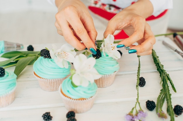 Ein junges Mädchen verziert Cupcakes mit frischen Beeren und Blumen