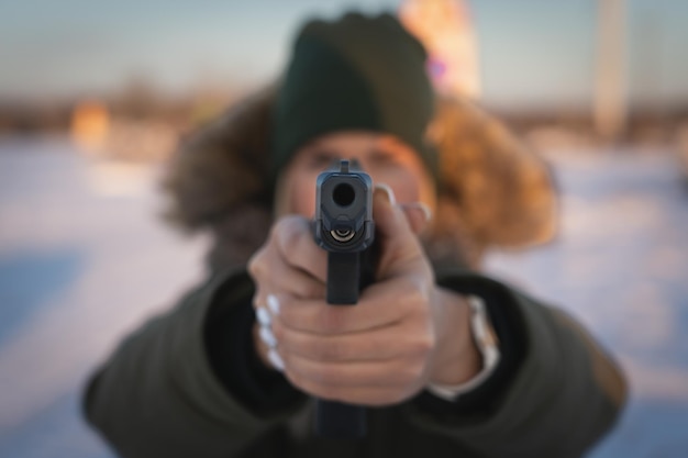 Foto ein junges mädchen zielt im winter draußen mit einer taktischen 9-mm-pistole. weichzeichnerfoto