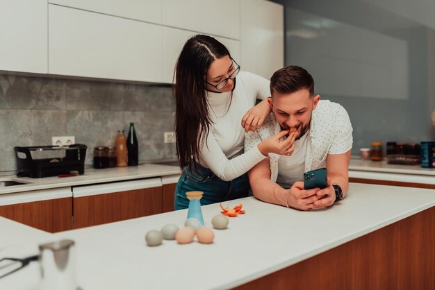 Ein junges Paar benutzt ein Smartphone, während es darüber nachdenkt, was es kochen soll