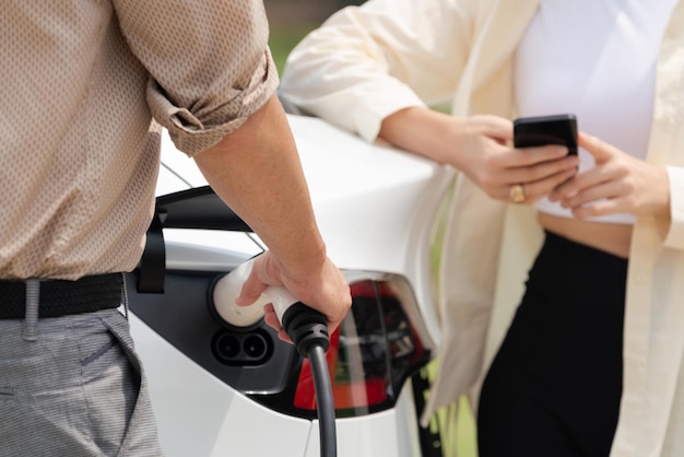 Ein junges Paar bezahlt mit dem Smartphone den Strom für ein EV-Fahrzeug