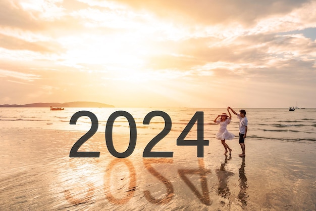 Foto ein junges paar, das auf dem ruhigen strand einen wunderschönen sonnenuntergang sieht und das neue jahr 2024 feiert