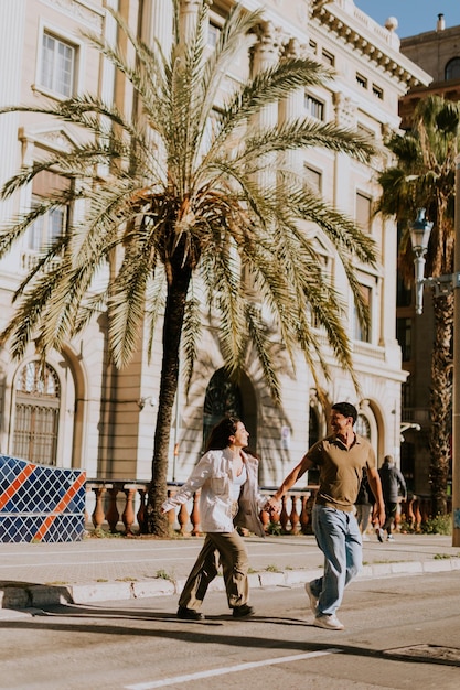 Ein junges Paar genießt einen sonnigen Spaziergang entlang der von Palmen gesäumten Promenade von Barcelona