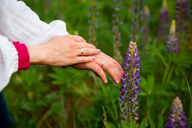 Ein junges Paar hat geheiratet und hält Händchen mit Eheringen in Blumen