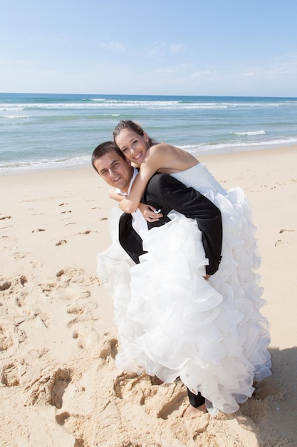 Ein junges Paar hat gerade am Strand Huckepack geheiratet