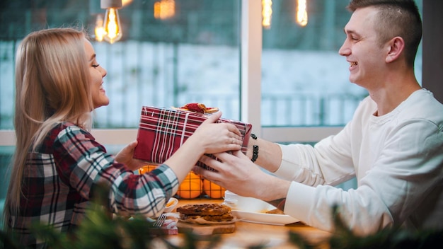 Ein junges Paar im Café gibt ein Mann seiner Freundin ein Weihnachtsgeschenk