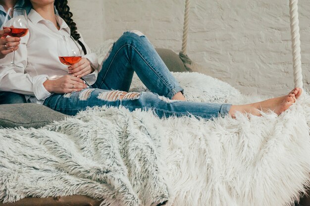 Ein junges Paar in Jeans mit Wein auf einem Bett