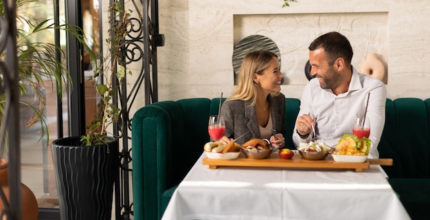 Ein junges Paar isst zu Mittag und trinkt frisch gepressten Saft im Restaurant