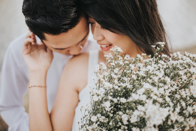 Ein junges Paar mit weißen Blumen, das im Freien romantisiert