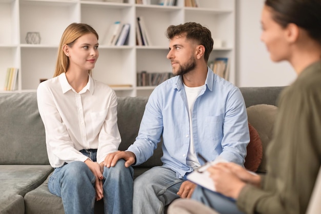 Ein junges Paar sitzt auf dem Sofa und nimmt an einer Paartherapie im Innenraum teil