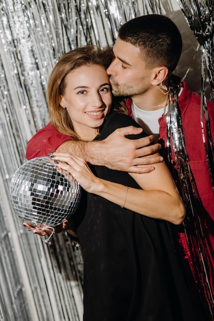 Ein junges romantisches europäisches Paar steht vor einem silbernen Vorhang