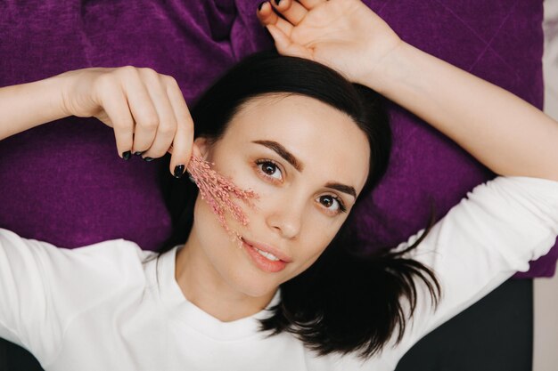 Ein junges schönes Mädchen mit einer Blume liegt auf dem Hintergrund Hautpflegekonzept Beauty Girl Portrait