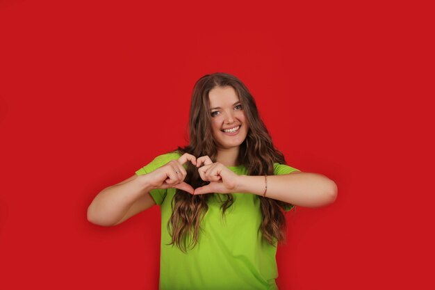 ein junges schönes Mädchen mit langen Haaren in einem hellgrünen T-Shirt in Blue Jeans zeigt Emotionen