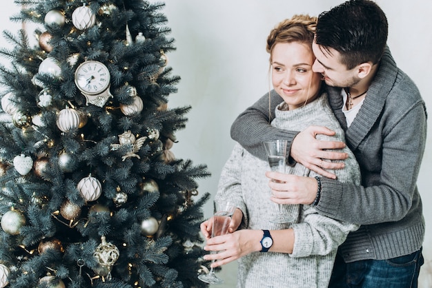 Ein junges schönes Paar, das neues Jahr nahe bei dem Weihnachtsbaum feiert