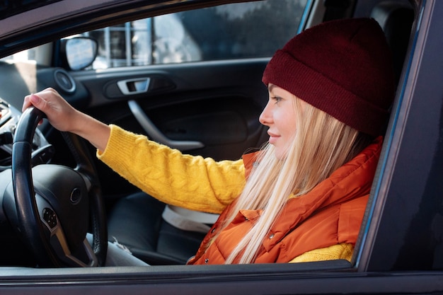 Ein junges sexy Mädchen in einem gelben Pullover sitzt hinter dem Steuer eines Autos und schaut auf die Straße. Autoversicherung.