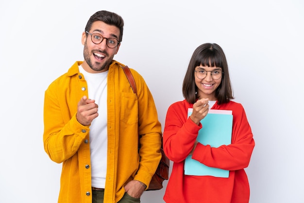 Ein junges Studentenpaar, das auf weißem Hintergrund isoliert ist, zeigt mit einem selbstbewussten Ausdruck mit dem Finger auf Sie