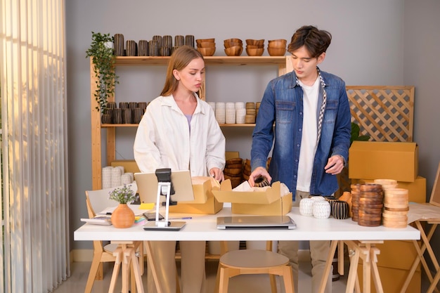 Ein junges Unternehmerpaar überprüft und verpackt handwerkliche Produkte, die an Kunden in ihrem Geschäft verkauft werden