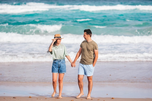 Ein junges verliebtes Paar auf dem Strand, Sommerurlaub, ein glücklicher Mann und eine glückliche Frau genießen die Zeit zusammen.