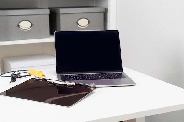 Ein kaputter Monitor und ein reparierter Laptop sitzen auf einem Tisch in einem hellen weißen Raum.